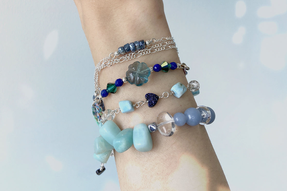 Wrist with multiple beaded bracelets on a light background